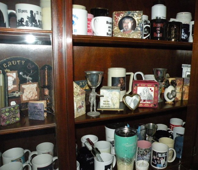 glass fronted cabinet with a collection of mugs and memorabilia plus a framed photo of Larry