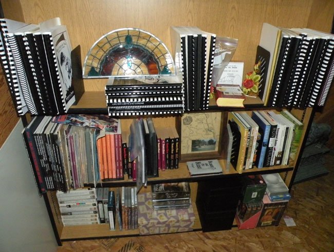 shelves with zines, books, batb stained glass